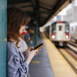 Woman checking her phone on an elevated subway platform